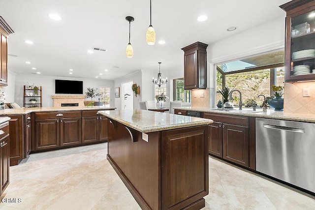 kitchen with hanging light fixtures, sink, stainless steel dishwasher, and dark brown cabinetry