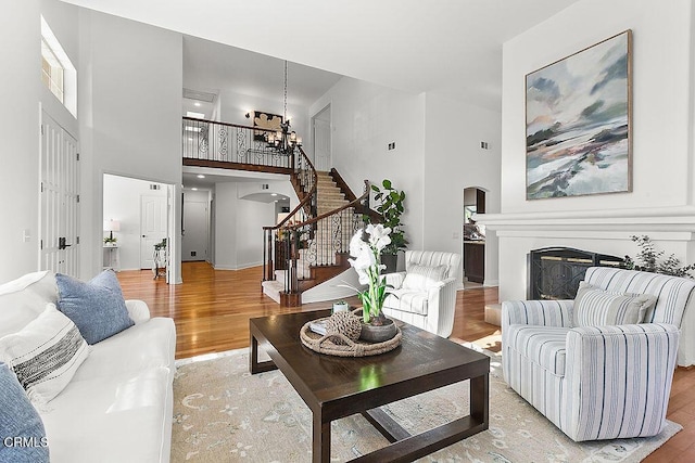 living room featuring a notable chandelier, a towering ceiling, and light hardwood / wood-style floors