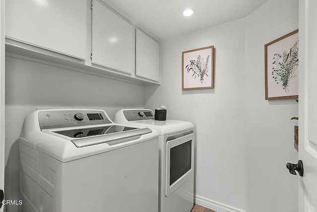 clothes washing area featuring cabinets and washing machine and clothes dryer