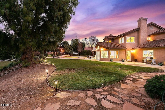 yard at dusk featuring a patio