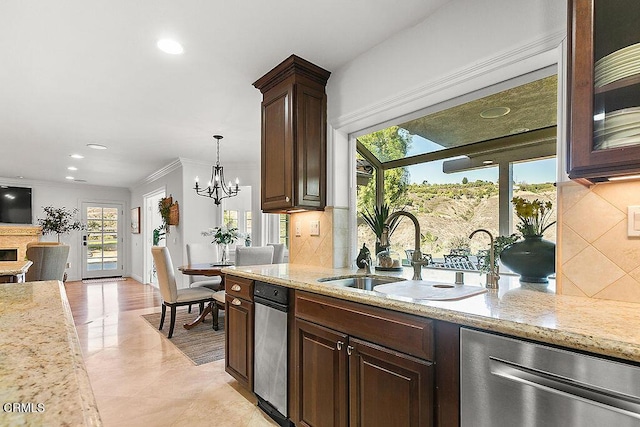 kitchen featuring pendant lighting, sink, light stone counters, tasteful backsplash, and stainless steel dishwasher