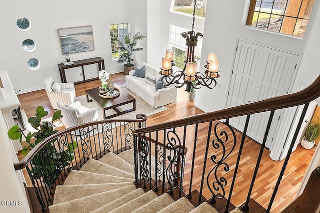 stairs featuring a high ceiling, a healthy amount of sunlight, hardwood / wood-style floors, and an inviting chandelier