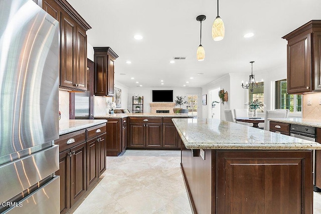 kitchen with dark brown cabinetry, a kitchen island, stainless steel refrigerator, and decorative light fixtures