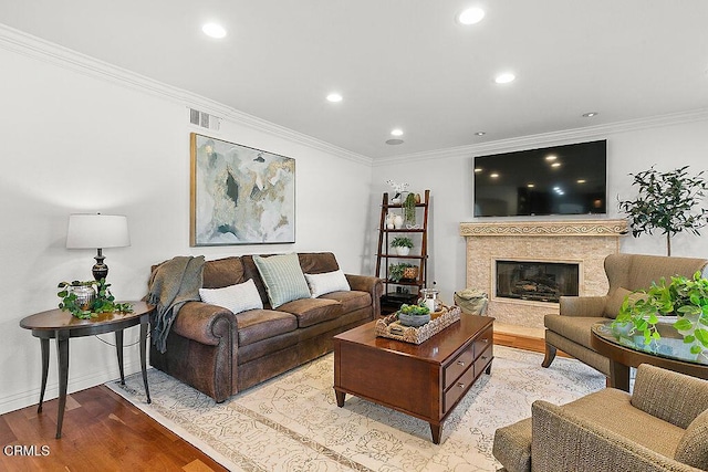 living room with crown molding, a fireplace, and light wood-type flooring