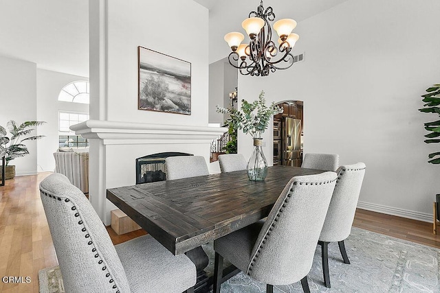 dining space featuring an inviting chandelier, a high ceiling, and light wood-type flooring