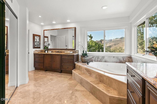 bathroom with vanity and a relaxing tiled tub