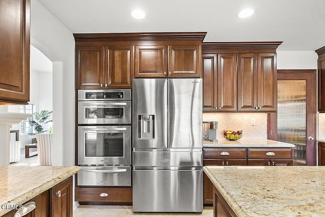 kitchen featuring tasteful backsplash, light tile patterned floors, light stone counters, and stainless steel appliances