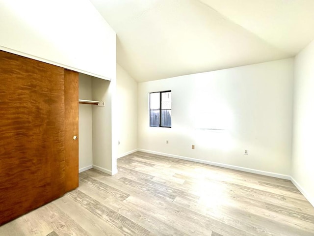 unfurnished bedroom featuring lofted ceiling, light hardwood / wood-style flooring, and a closet