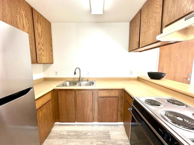 kitchen featuring stainless steel refrigerator, sink, and electric range