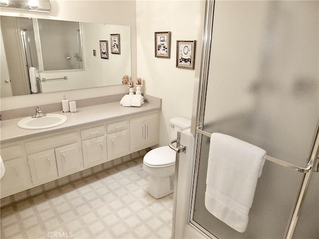 bathroom with vanity, a shower with door, and toilet