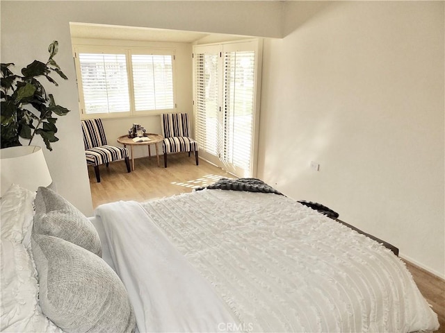 bedroom with multiple windows and light hardwood / wood-style flooring