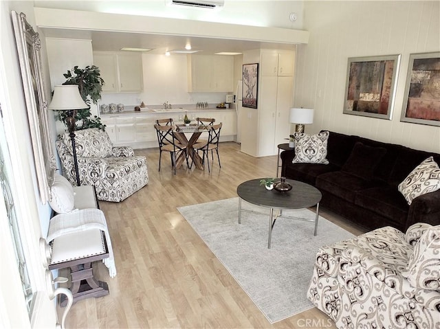 living room featuring sink, a wall mounted air conditioner, and light hardwood / wood-style floors