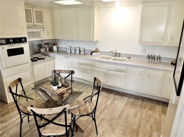 kitchen with sink, white cabinets, white appliances, and light hardwood / wood-style flooring