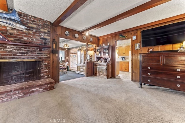 carpeted living room with a brick fireplace, wood walls, a textured ceiling, and beam ceiling