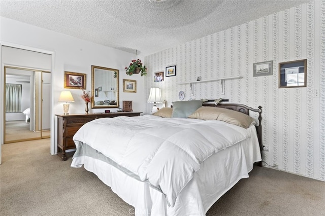 bedroom with light colored carpet, a textured ceiling, and wallpapered walls