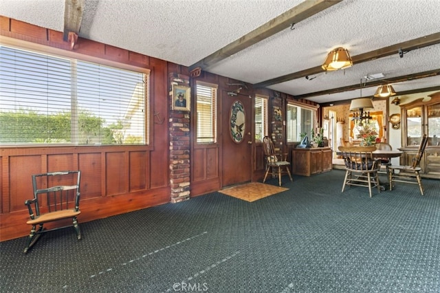 foyer with wood walls, carpet, a textured ceiling, and beamed ceiling