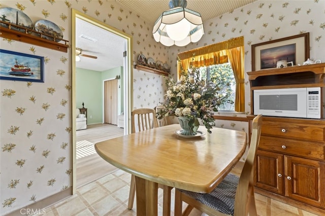 dining room with baseboards, visible vents, and wallpapered walls