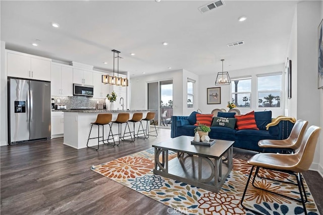 living room featuring sink, plenty of natural light, dark hardwood / wood-style floors, and a chandelier