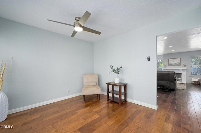 living area with ceiling fan, dark hardwood / wood-style floors, and a textured ceiling