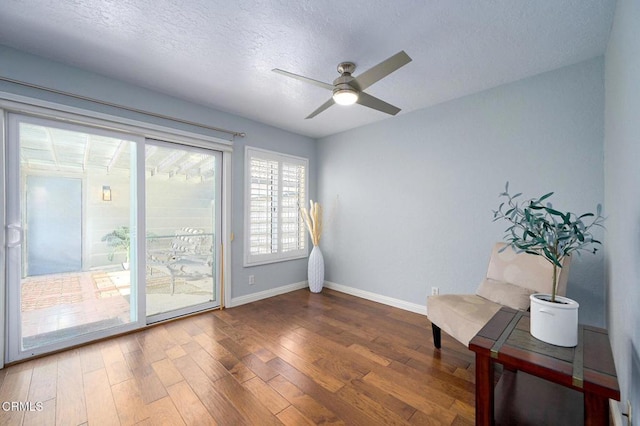 sitting room featuring ceiling fan, wood-type flooring, and a textured ceiling