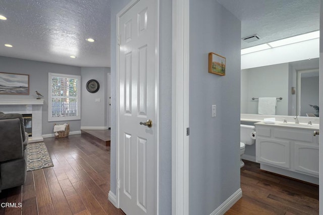 corridor featuring dark hardwood / wood-style flooring, sink, and a textured ceiling