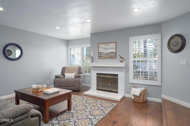 living room with wood-type flooring, a tile fireplace, and a textured ceiling