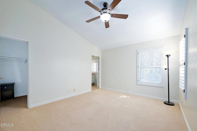 unfurnished bedroom featuring lofted ceiling, a spacious closet, light carpet, and ceiling fan