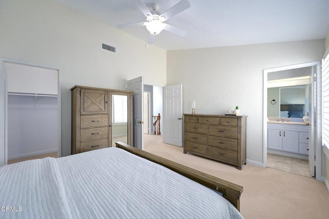 carpeted bedroom with lofted ceiling, connected bathroom, a walk in closet, a closet, and ceiling fan