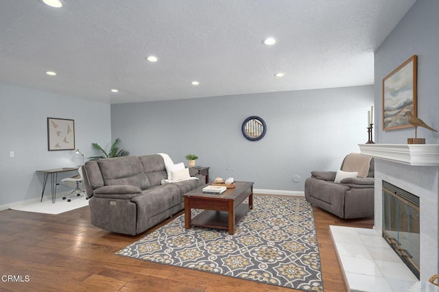 living room featuring light hardwood / wood-style floors, a tile fireplace, and a textured ceiling