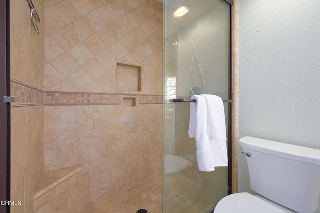 bathroom with a shower with door and toilet