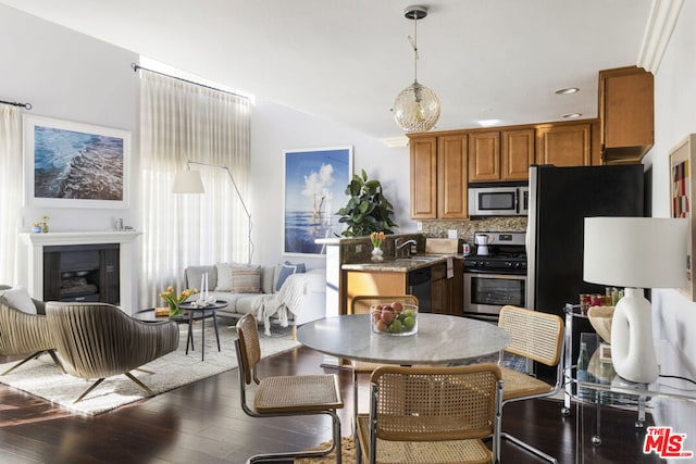 kitchen with sink, appliances with stainless steel finishes, light stone counters, dark hardwood / wood-style flooring, and decorative backsplash