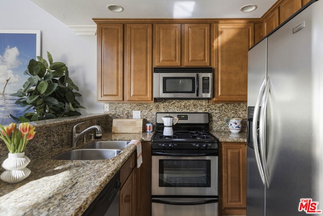 kitchen with stainless steel appliances, tasteful backsplash, sink, and light stone counters