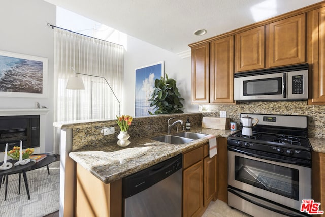 kitchen featuring stone countertops, appliances with stainless steel finishes, sink, and kitchen peninsula