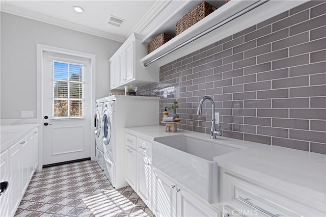 laundry area featuring independent washer and dryer, sink, ornamental molding, and cabinets