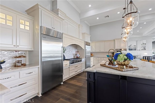 kitchen with hanging light fixtures, dark hardwood / wood-style floors, stainless steel appliances, a kitchen island with sink, and backsplash