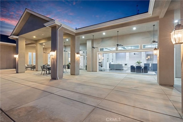 back house at dusk featuring ceiling fan and a patio area