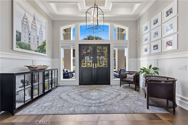 living area featuring crown molding, hardwood / wood-style flooring, coffered ceiling, a notable chandelier, and french doors