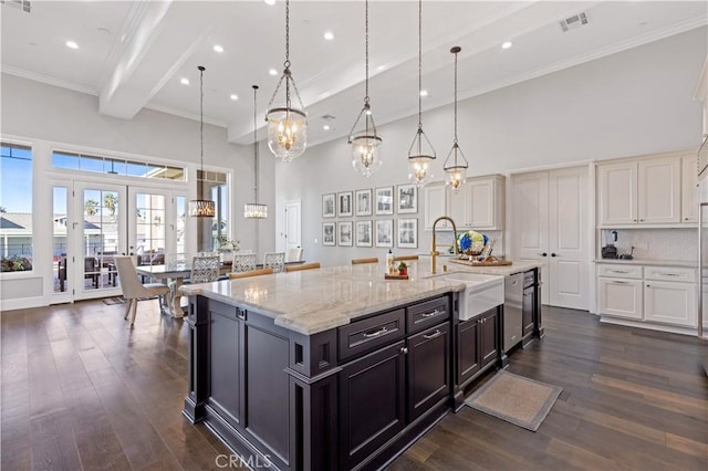 kitchen featuring pendant lighting, white cabinetry, sink, a large island with sink, and light stone counters