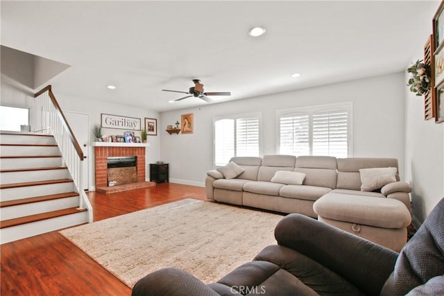 living room with a fireplace, wood-type flooring, and ceiling fan