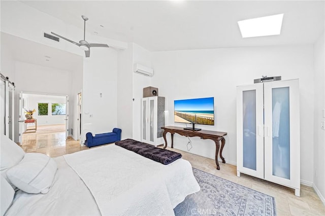 bedroom featuring ceiling fan, a skylight, high vaulted ceiling, a wall mounted air conditioner, and a barn door