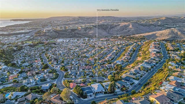 aerial view at dusk featuring a water and mountain view