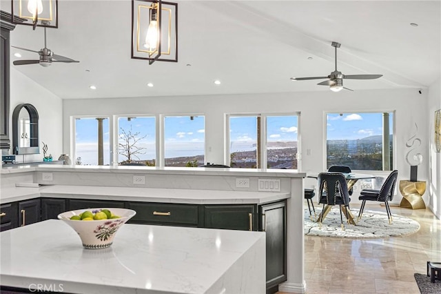 kitchen with pendant lighting, lofted ceiling, ceiling fan, light stone countertops, and a kitchen island