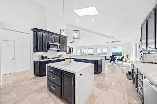 kitchen with appliances with stainless steel finishes, hanging light fixtures, a skylight, a center island, and kitchen peninsula