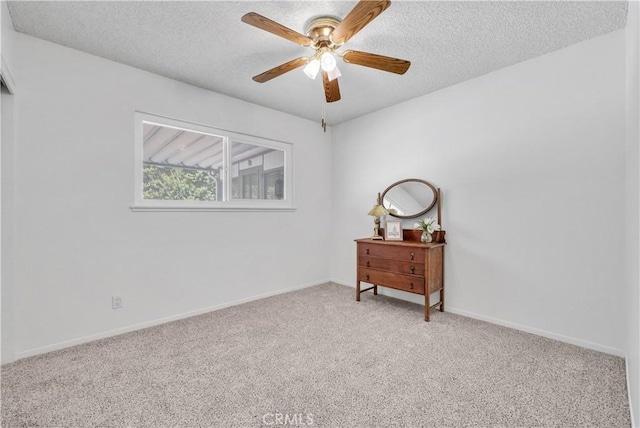 carpeted spare room featuring a textured ceiling, baseboards, and a ceiling fan