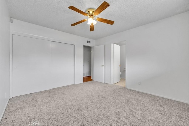 unfurnished bedroom featuring a closet, visible vents, a textured ceiling, and carpet floors