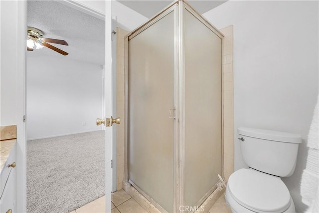 full bathroom with vanity, a ceiling fan, a stall shower, tile patterned floors, and toilet