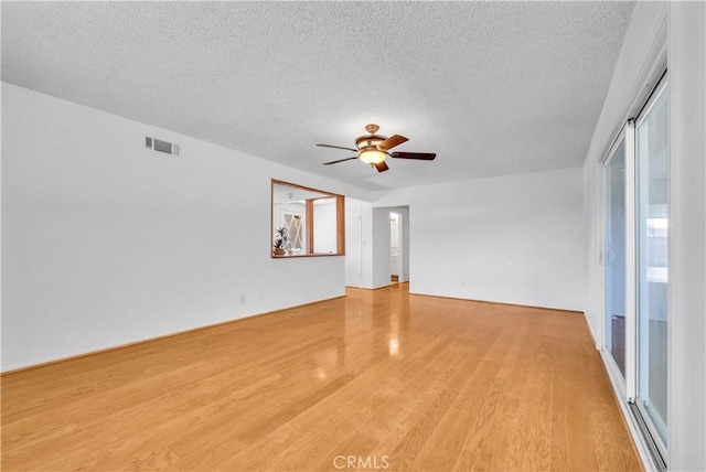 empty room with light wood finished floors, visible vents, a textured ceiling, and ceiling fan