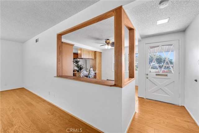 entrance foyer featuring ceiling fan, a textured ceiling, and wood finished floors