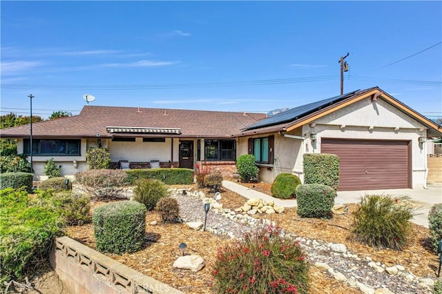 single story home featuring stucco siding, a garage, solar panels, and driveway