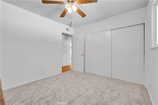 unfurnished bedroom with visible vents, a ceiling fan, a textured ceiling, a closet, and carpet flooring